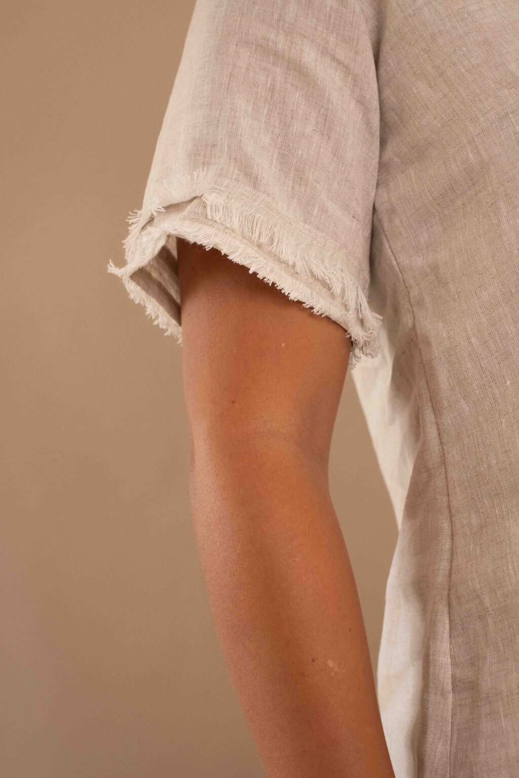 Top Serenidad de lino color crudo con drapeado ajustable y bordes deshilados.