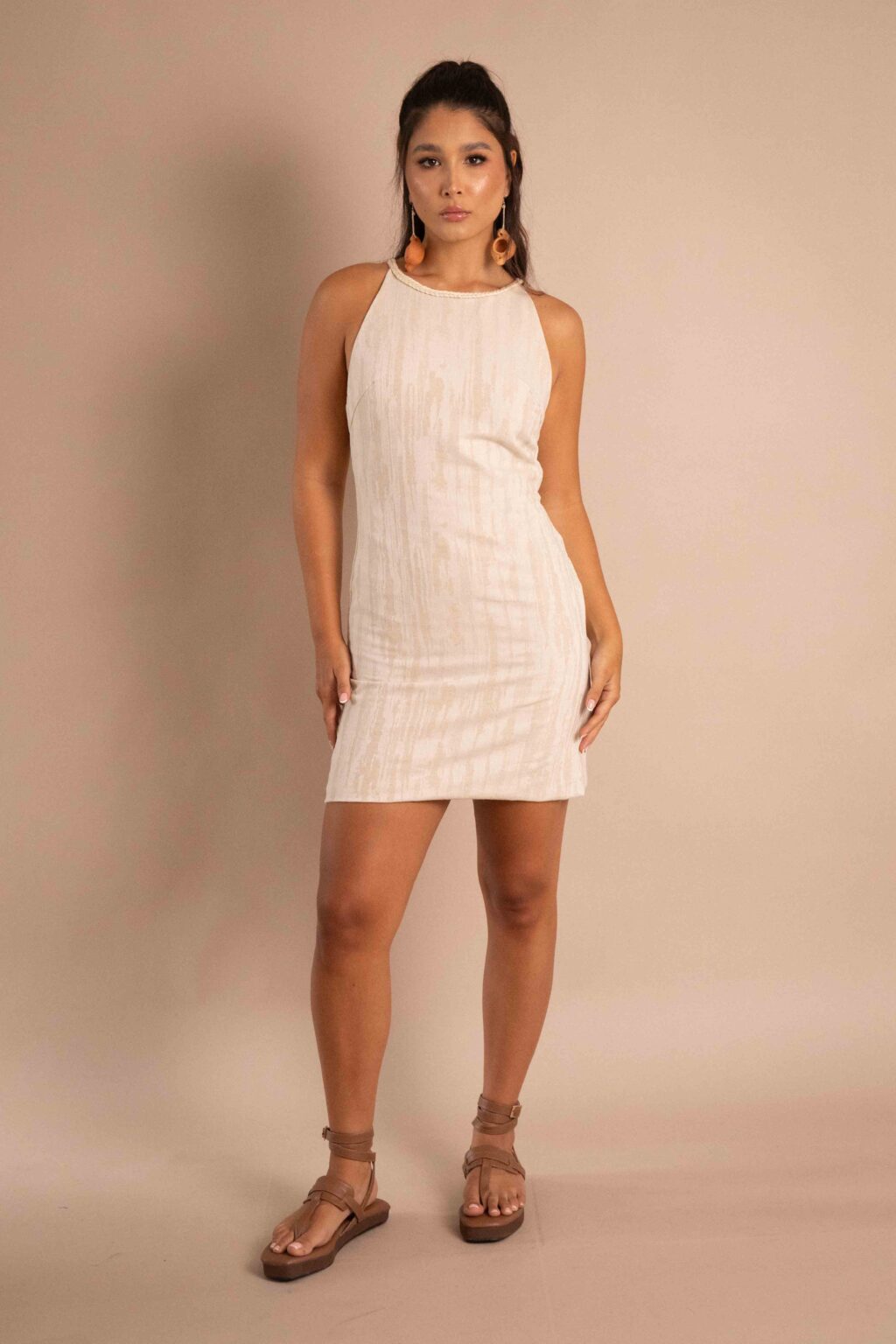 Vestido Creación de lino color natural con detalles trenzados frontales.